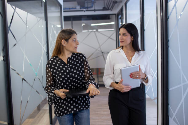 istock Two women talking in the office hallway 1337340024