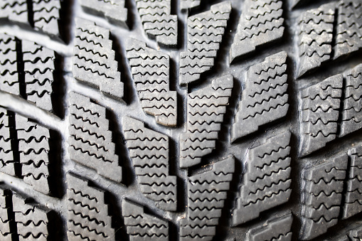 A stud-less winter snow tire close up showing the tread pattern.