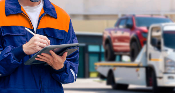 insurance officer using electronic pen to recording data of broken pickup car on tablet while prepare for transporting to garage after accident