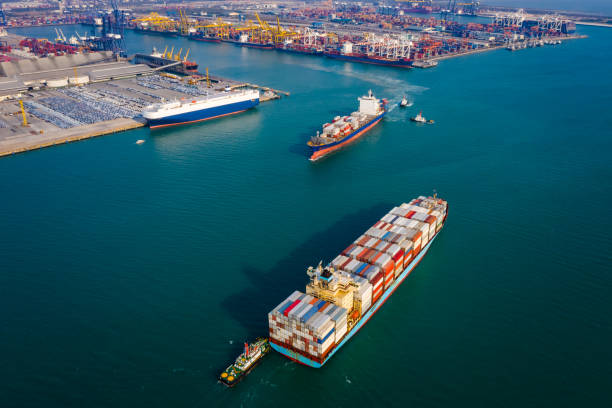 istock Aerial view two container ship and tug boat to quayside for load and unloading container via crane for logistics, import export, shipping or transportation in Thailand 1337353225