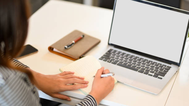 istock Young businesswoman taking notes in laptop computer, laptop blank screen mockup 1337354202