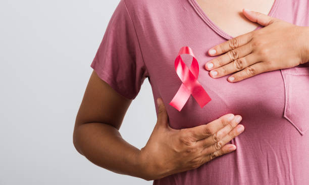 woman wear pink t-shirt she have pink breast cancer awareness ribbon on chest she hold breast by hand stock photo