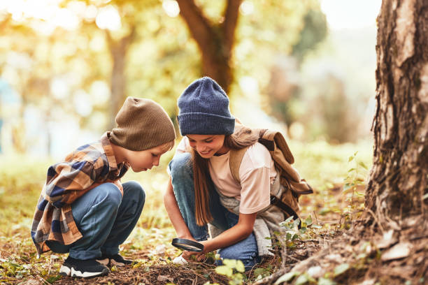 istock Two little kids in warm hats with backpacks examining tree bark 1337363601