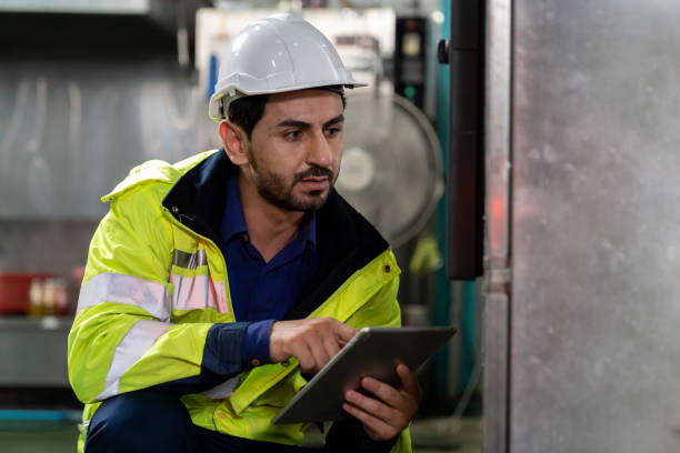 istock Technicians male worker working with digital tablet. Engineering male worker repairing, maintenance and checking the operation of equipment in the industrial factory, wearing safety uniform and helmet 1337365356