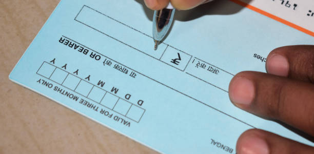 Closeup on man`s hands writing a cheque. A generic blank cheque being signed.