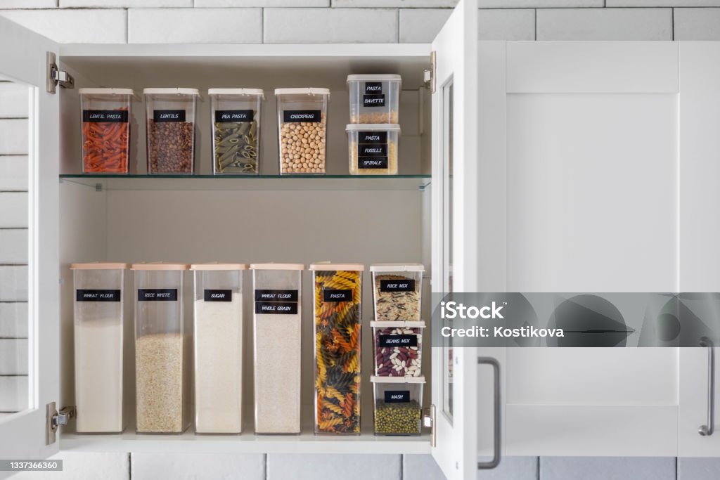 Kitchen storage organization use plastic case. Placing and sorting food products into pp box Kitchen storage organization use plastic case. Placing and sorting food products into pp box. Keeping organizing at modern kitchen interior in Nordic style. General cleaning, tidying up at cuisine Kitchen Stock Photo