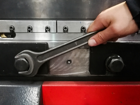 detail of a hand with a spanner loosening the screw of a machine