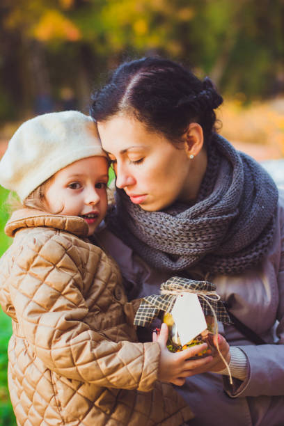 istock Mother and daughter keep bottle filled autumn treasures with empty label 1337368114
