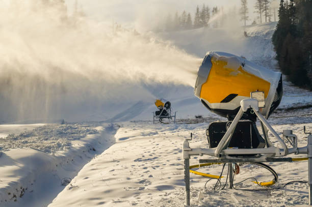Snow cannon in winter mountains. Snow-gun spraying artificial ice crystals. Machine making snow.