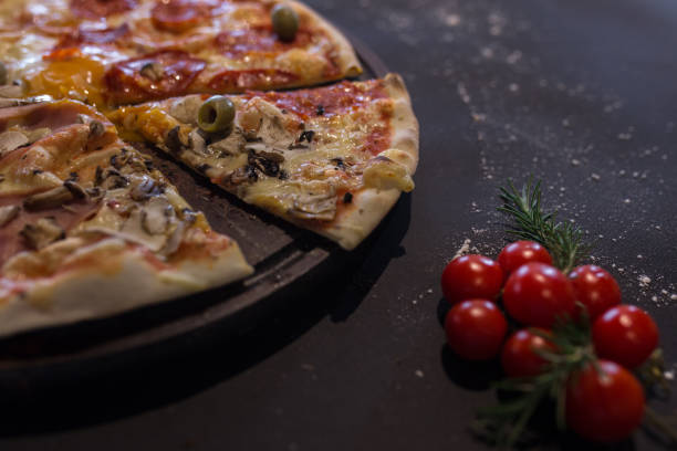 nahaufnahme eines quattro stagioni pizzascheibens auf schwarzem hintergrund - salami sausage portion decoration stock-fotos und bilder