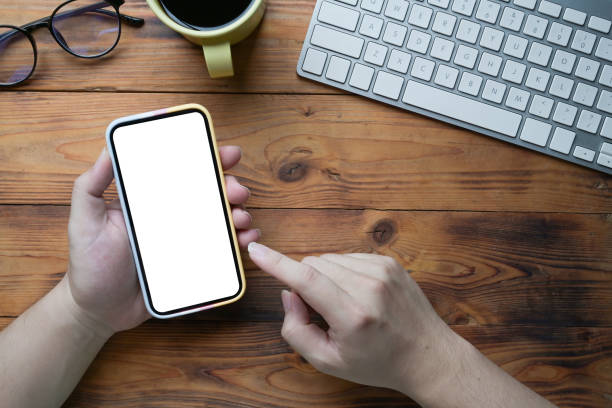 istock Above view young man using smart phone on wooden desk. 1337372951