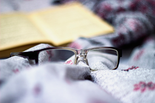 Concept of reading a book lying on a bed with glasses