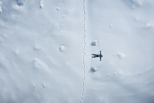 Aerial view on a woman lying on back in the fresh snow (snow angel).