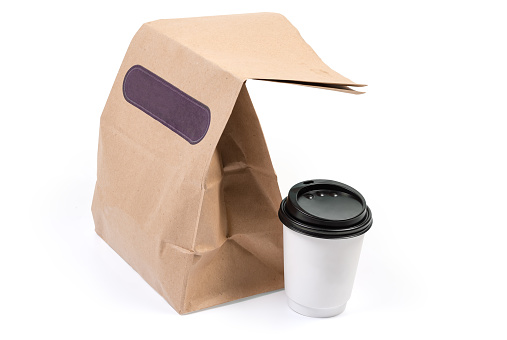 Disposable brown paper food packaging bag and paper cup with closed lid with street food on a white background