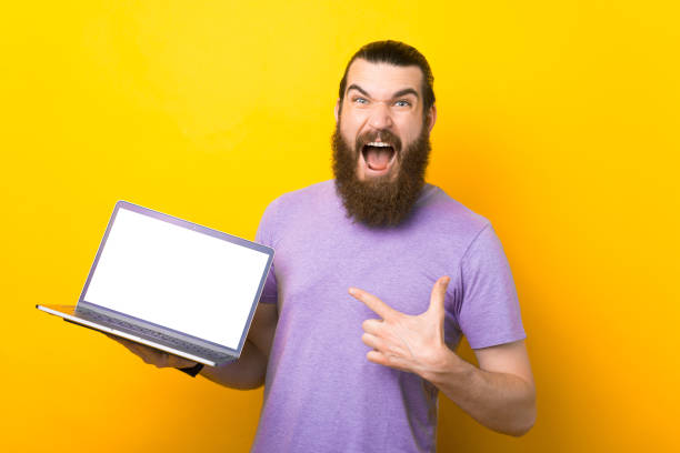 istock Screaming bearded man is pointing at the laptop. 1337380054