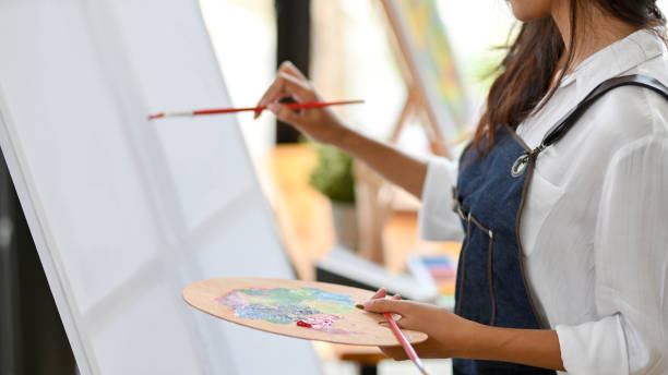 istock Painter artist painting on canvas easel, holding colour palette 1337381298