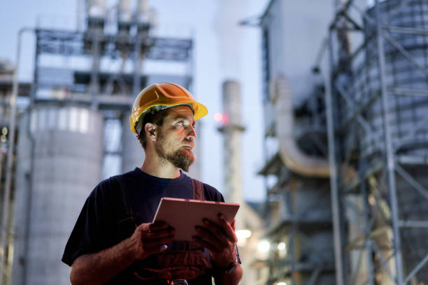 ingenieur, der nachts mit einem digitalen tablet arbeitet - petrochemical plant stock-fotos und bilder