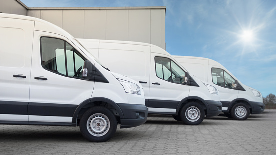 White delivery vans with a neutral distribution warehouse in the background