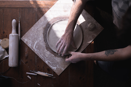 The process of making ceramic plate, man pinching clay