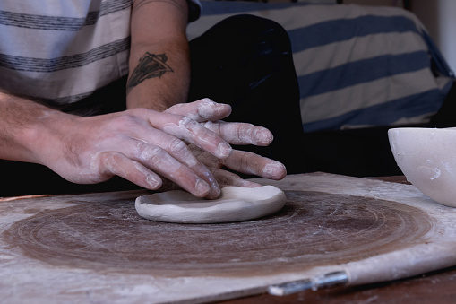 Hands moving as man works with ceramic clay
