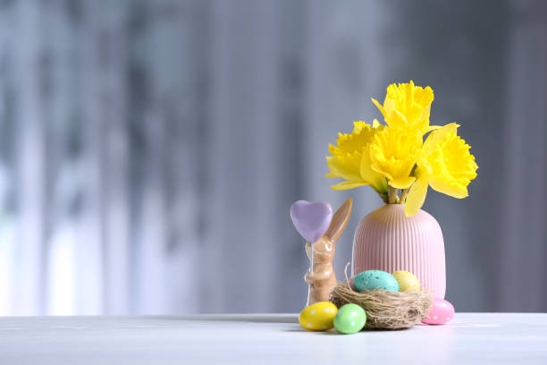 istock Painted Easter eggs, ceramic bunny and flowers on white table against blurred background. Space for text 1337387022