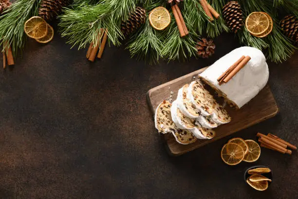 Christmas traditional stollen on brown background with copy space. Xmas greeting card. View from above. Flat lay style.