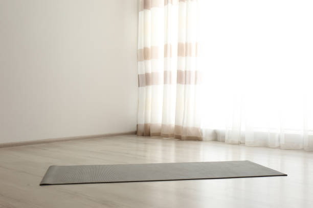 istock Unrolled grey yoga mat on floor in room. Space for text 1337399788