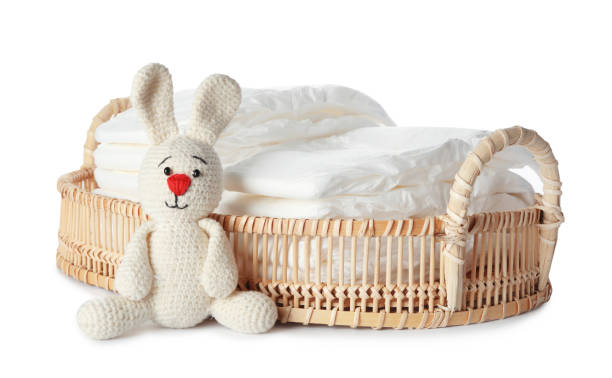istock Wicker tray with disposable diapers and toy bunny on white background 1337401531