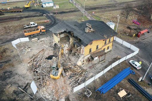 Yellow excavator destroys building. Heavy duty machine is demolishing a brick building. Demolition of the building . Demolition construction work aerial drone photo view