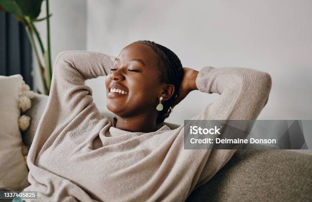 Shot Of A Young Woman Relaxing On The Sofa At Home Stock Photo - Download Image Now - Relaxation, Wellbeing, Women