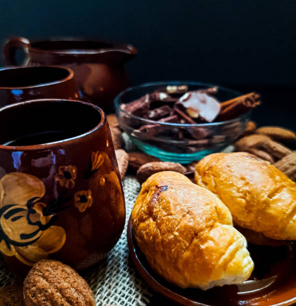 istock Coffee in a small brown mugs with cinnamon, croissants for one on a dark background 1337407298