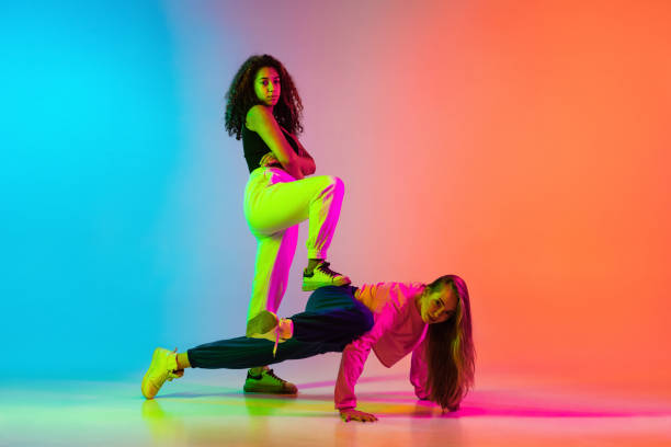 istock Expressive dance. Two young girls dancing hip-hop on colorful gradient background 1337407445