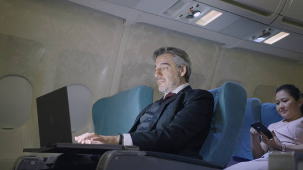 Mature businessman using his laptop in flight stock photo