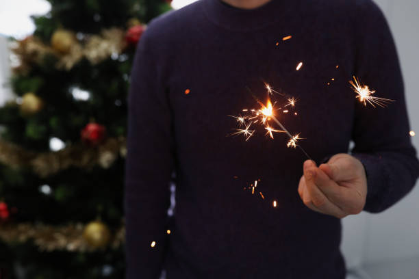 Man holds lighted sparkler in dark. New Year and Christmas celebration concept
