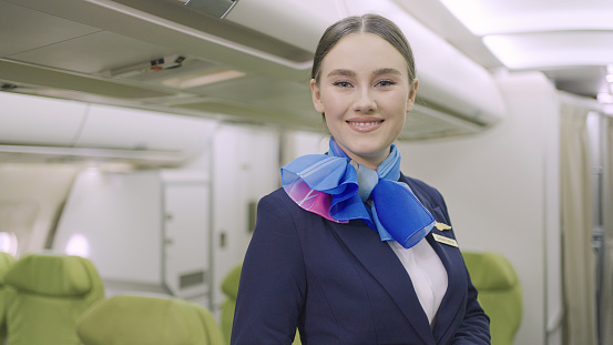 Portrait of a confident and friendly smiling female air hostess in flight looking at camera.