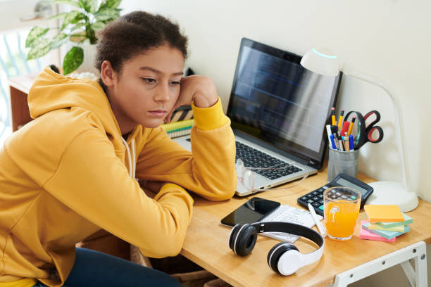 Bored Schoolgirl Studying at Home stock photo