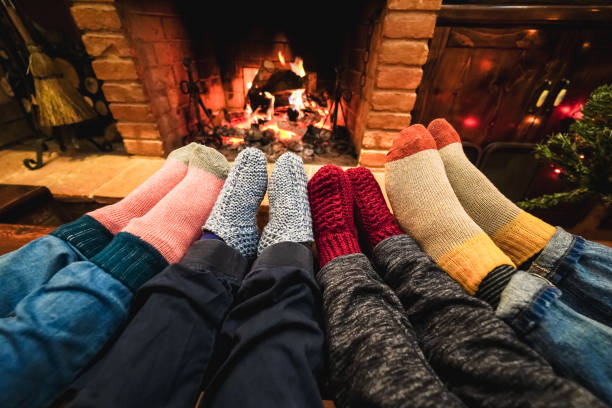 Legs view of happy family wearing warm socks in front of fireplace - Focus on left socks stock photo