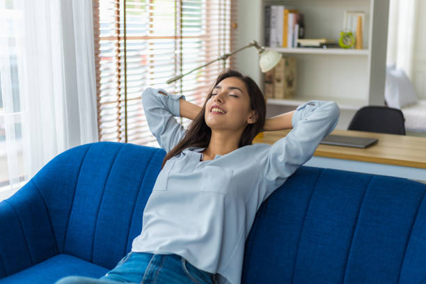 Cacusian woman take a nap during the daytime to rest their eyes from hard work. Woman relaxing on sofa with eyes closed and hands behind head at home. She twisted lazily and lay down breath of fresh stock photo