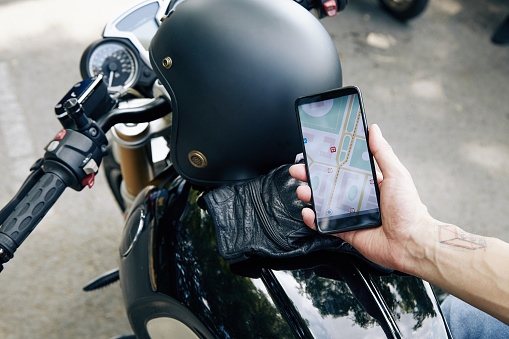 Courier with smartphone in hands checking map on smartphone when searching for certain address
