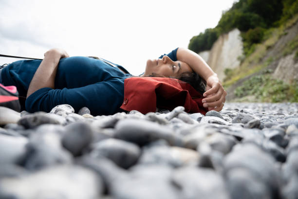 woman resting at pebble beach at chalk rock coast side view on woman lying down for a rest at pebble beach at chalk rock coast baltic sea people stock pictures, royalty-free photos & images