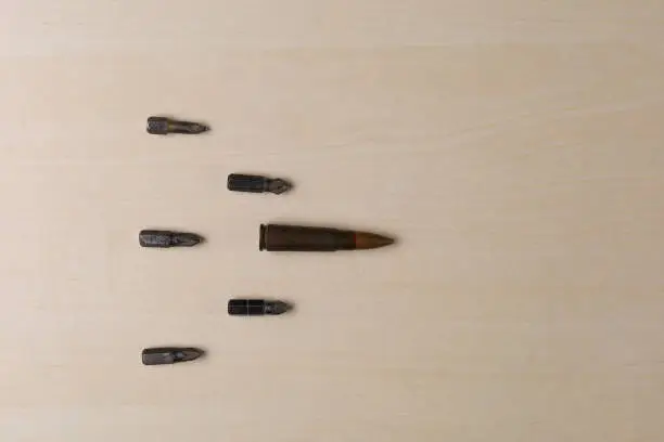 Photo of Military rifle bullet and screwdriver attachments on wooden background. Abstract concept of hard workers protest power