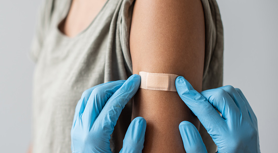 Trabajador de la salud médica colocando vendaje en el brazo femenino después de la vacunación contra el covid-19 photo