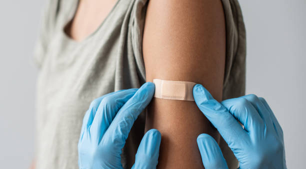 trabajador de la salud médica colocando vendaje en el brazo femenino después de la vacunación contra el covid-19 - vacunación fotografías e imágenes de stock