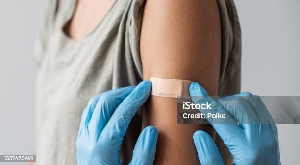 Medical Healthcare Worker Putting Bandage On The Female Arm After Covid19 Vaccination Stock Photo - Download Image Now