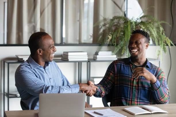 Smiling ethnic male colleagues handshake at office meeting