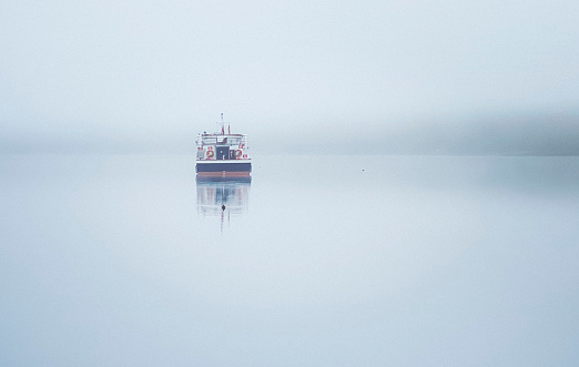 A boat resting on a calm foggy lake