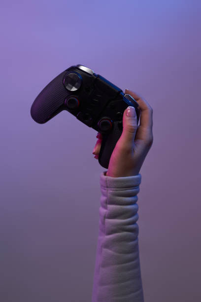 istock Hand with a game joystick on violet background. 1337429687