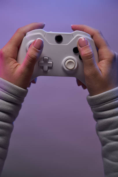 istock Hands with white game joystick on violet background. 1337429724