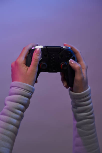 istock Hands with a game joystick on violet background. 1337429758