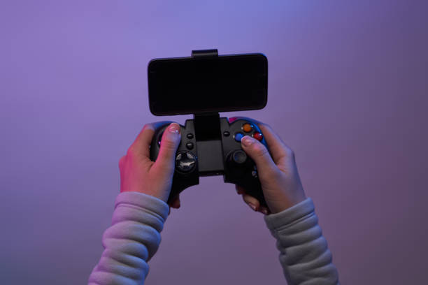 istock Hands with a game joystick on violet background. 1337429897